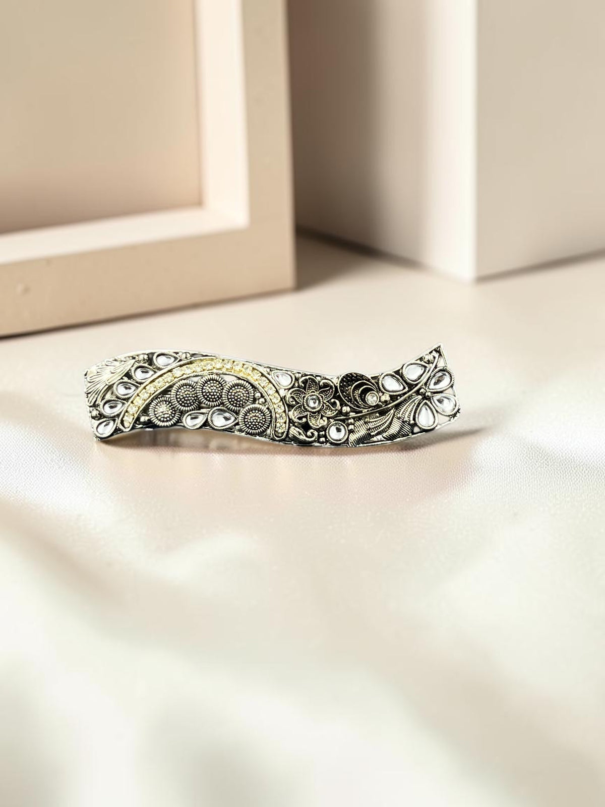 SHE BEAUTY curved vintage metallic barrette featuring intricate floral engravings and white stone accents.
