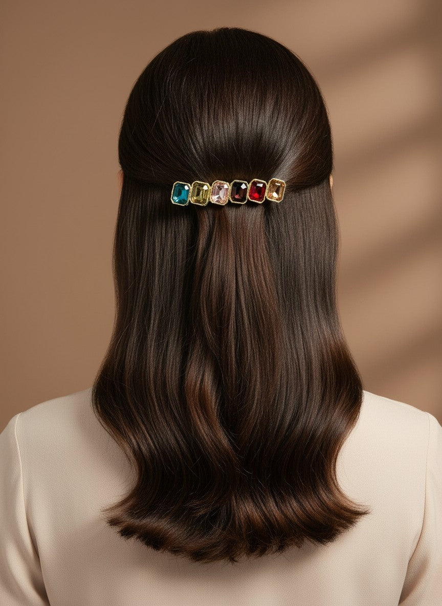 SHE BEAUTY barrette featuring six rectangular multi-colored gemstones worn in long dark hair for a festive look.