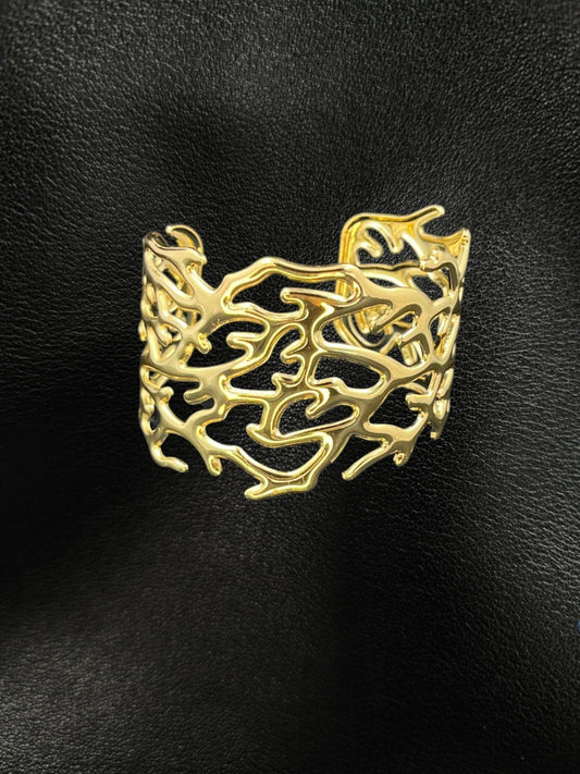 SHE BEAUTY golden cuff bracelet featuring an intricate organic geometric cutout design on a black leather background