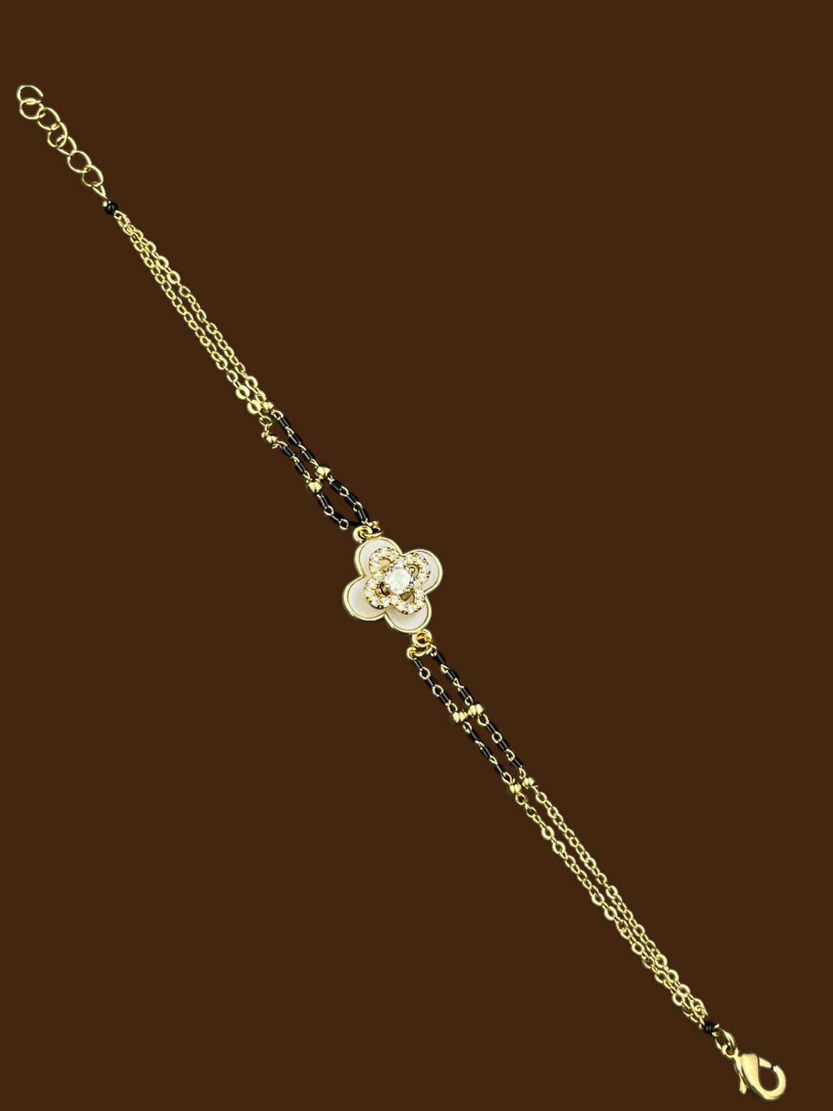 SHE BEAUTY anti-tarnish mangalsutra bracelet featuring a gold-tone chain with black beads and a floral AD stone charm