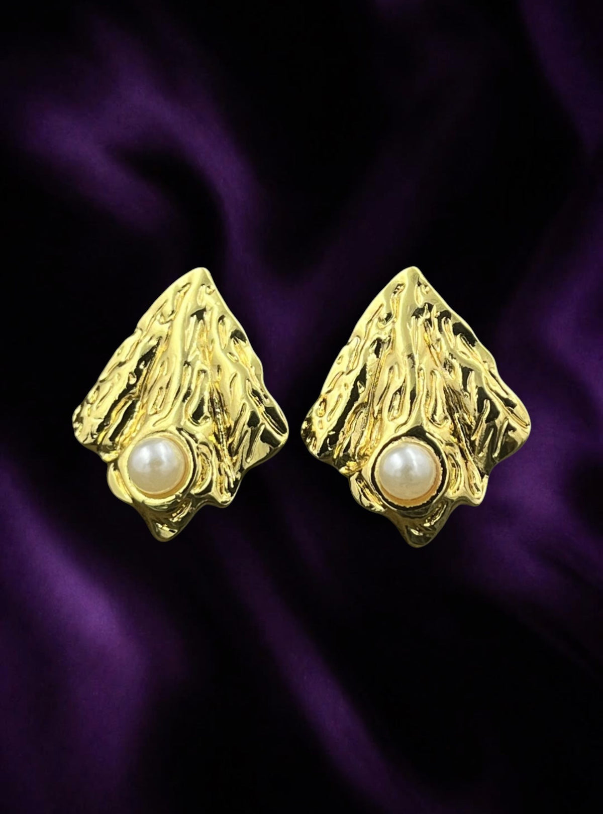 SHE BEAUTY anti-tarnish gold-toned textured earrings with central pearl accents on a purple satin background