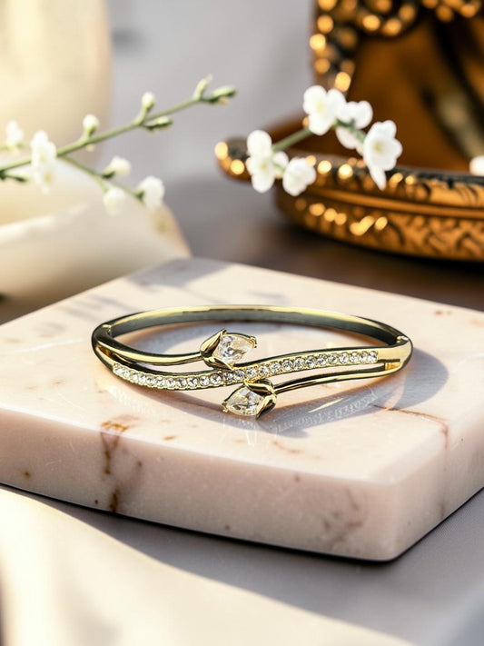 SHE BEAUTY gold anti-tarnish bracelet featuring a bypass design with sparkling zirconia stones on a marble display