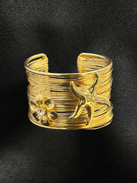 SHE BEAUTY golden multi-layer wire cuff bracelet featuring a starfish and a crystal-centered flower charm.