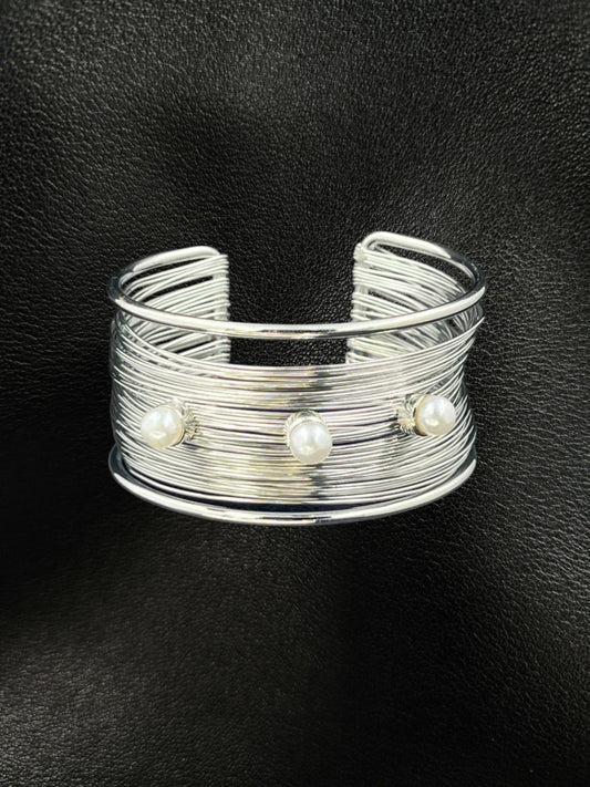 SHE BEAUTY multilayer silver cuff bracelet featuring three white pearls on a textured wire band against black leather.