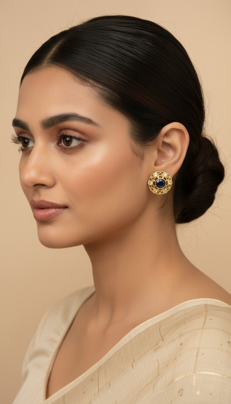 SHE BEAUTY antique gold-toned stud earrings featuring a central blue stone and clear accents on a model