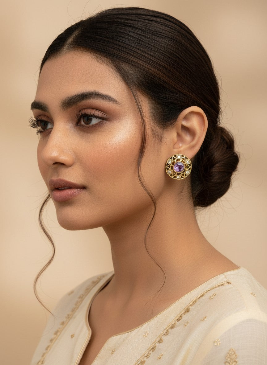 SHE BEAUTY antique gold-toned stud earrings with a central purple stone and clear crystal accents on a model