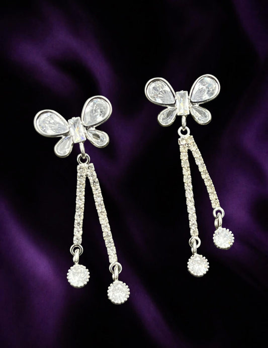 SHE BEAUTY AD butterfly earrings with sparkling cubic zirconia stones on a deep purple fabric background