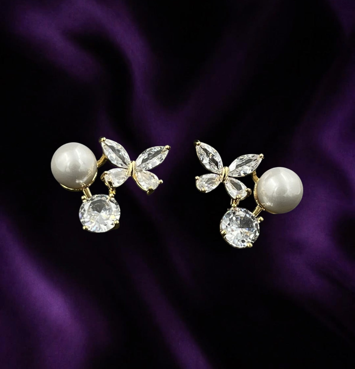 SHE BEAUTY Korean AD post earrings featuring butterfly crystals, round pearls, and clear stones on purple silk