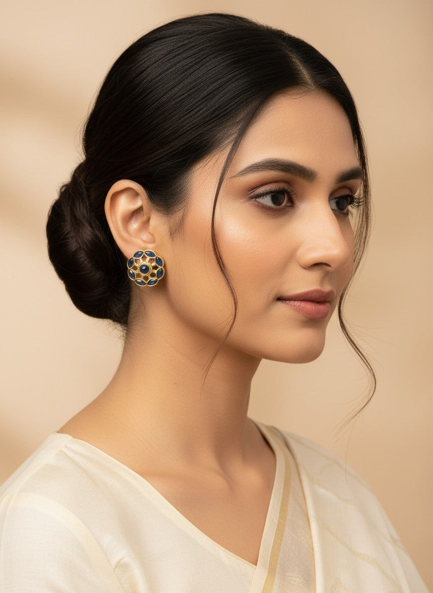 SHE BEAUTY COLOUR STUDS featuring a gold-tone floral design with blue stones worn by a woman in a cream outfit.