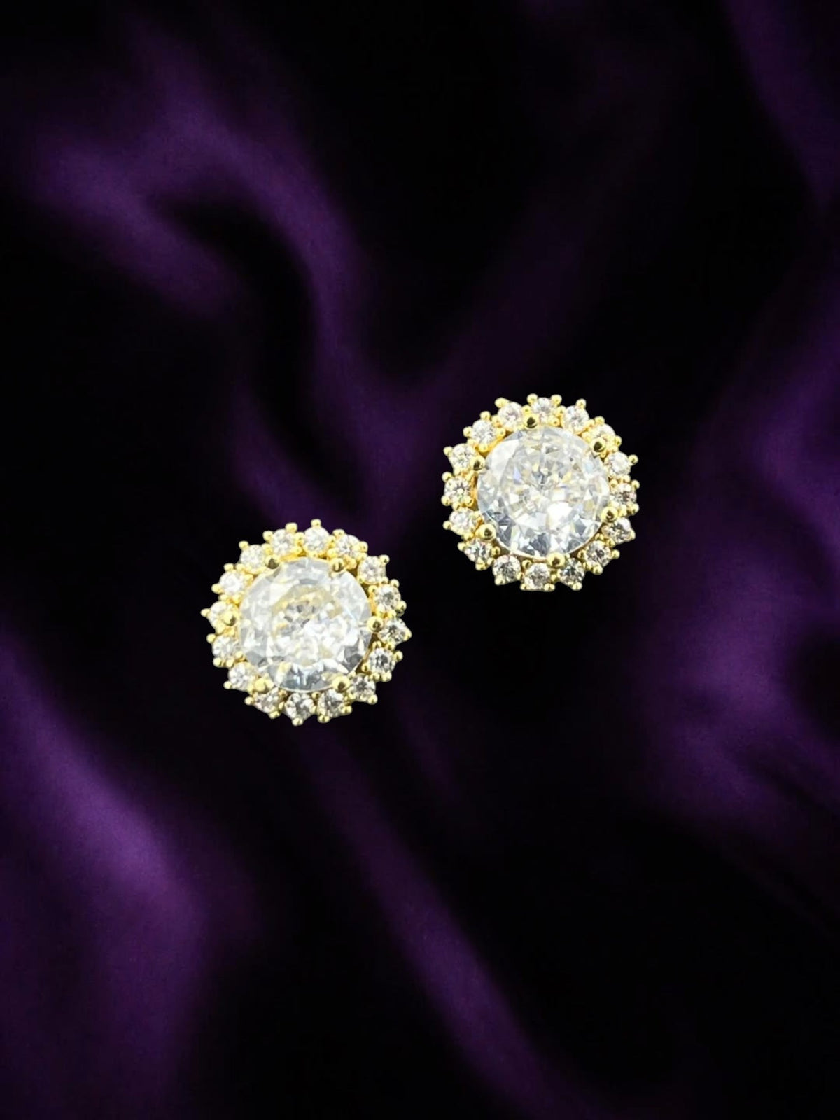 SHE BEAUTY CRYSTAL HALO gold-toned stud earrings featuring a central round stone surrounded by a halo of crystals.