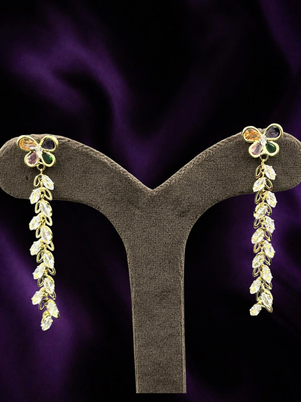 SHE BEAUTY Crystal Trails earrings featuring gold-tone butterfly studs with multi-colored gems and dangling crystals.