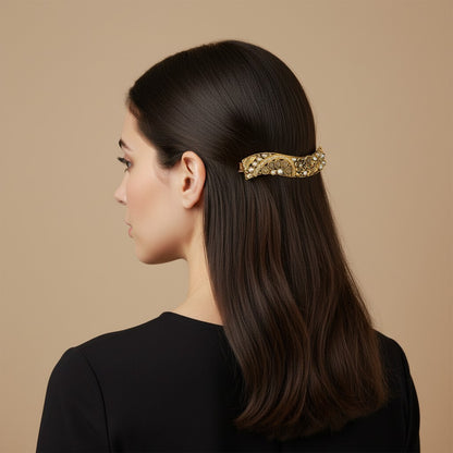 SHE BEAUTY curved vintage metallic barrette with intricate gold filigree and pearl accents worn in dark hair