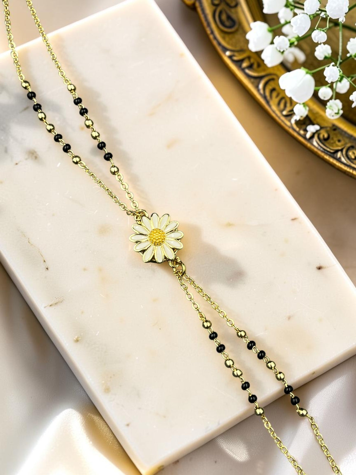 SHE BEAUTY anti-tarnish gold-toned mangalsutra bracelet featuring a delicate white daisy flower charm and black beads.