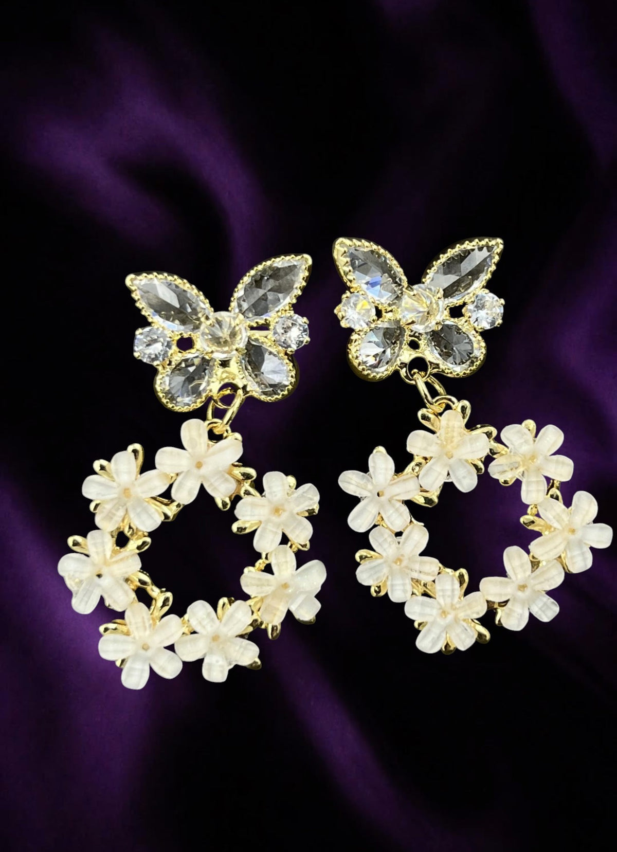 SHE BEAUTY Flora butterfly earrings featuring crystal-embellished butterflies and white floral wreaths in gold tone