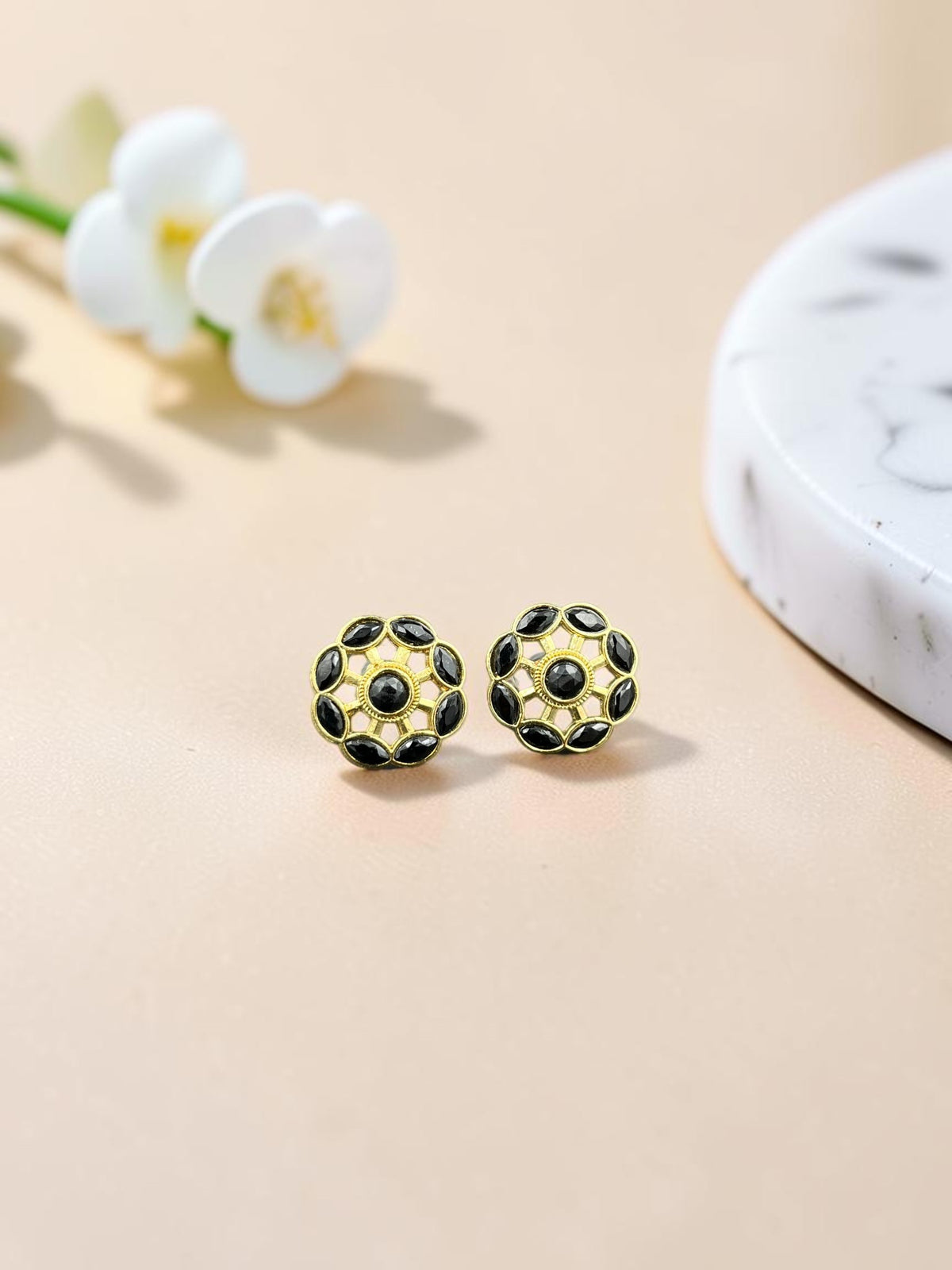 SHE BEAUTY gold-toned floral stud earrings with black stone accents, perfect for ethnic and festive occasion wear.