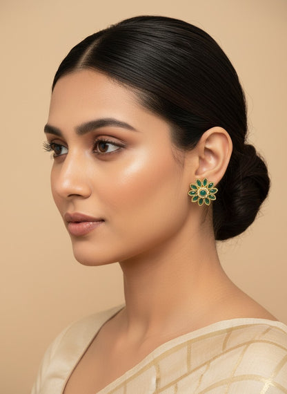 SHE BEAUTY floral stud earrings with green stones and gold-toned metal worn by a woman with a sleek bun hairstyle