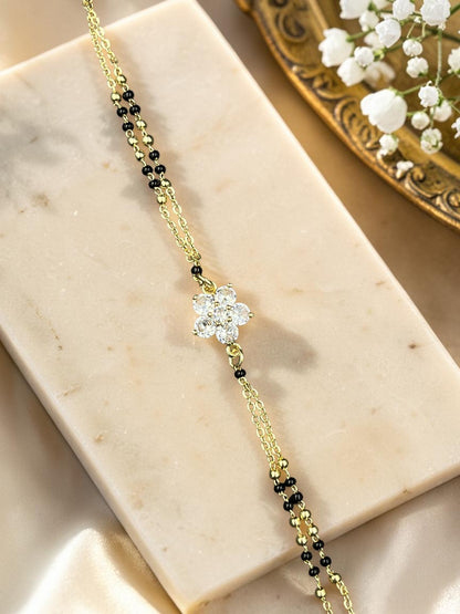 SHE BEAUTY anti-tarnish gold-tone mangalsutra bracelet featuring a floral American diamond charm and black beads.