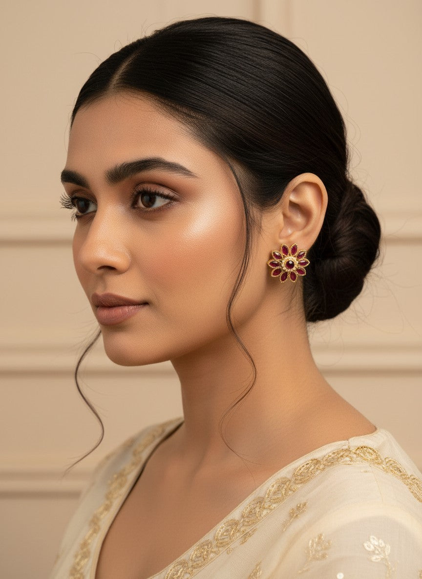 SHE BEAUTY floral stud earrings with deep red stones and gold-toned petals worn by a woman in ethnic attire