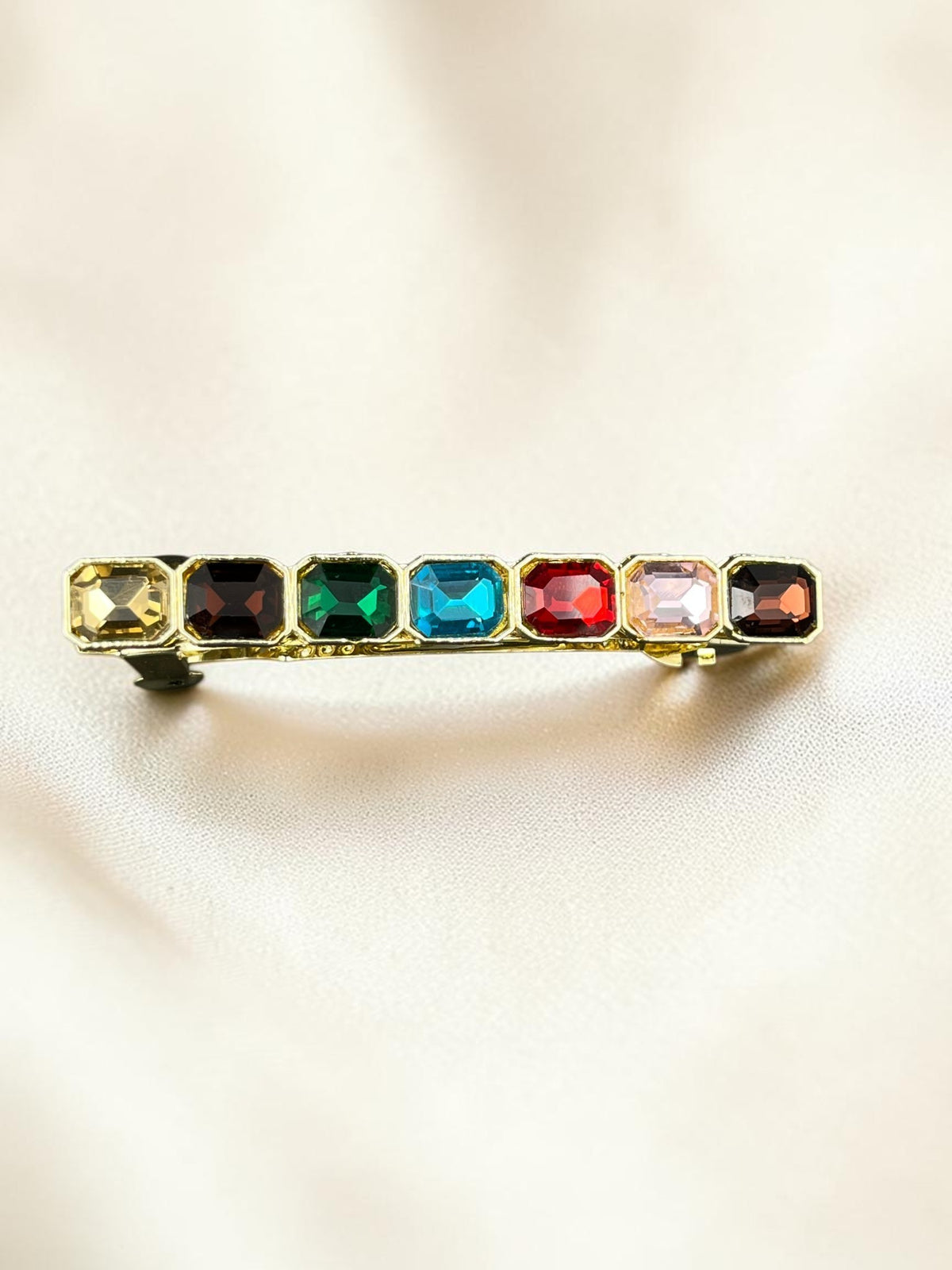 SHE BEAUTY barrette featuring seven rectangular multi-colored gemstones in a gold-tone setting for festive hair styling