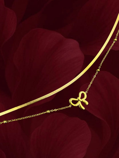 SHE BEAUTY KIYU ZIYU gold-toned layered anklet featuring a delicate bow charm and a sleek snake chain design.