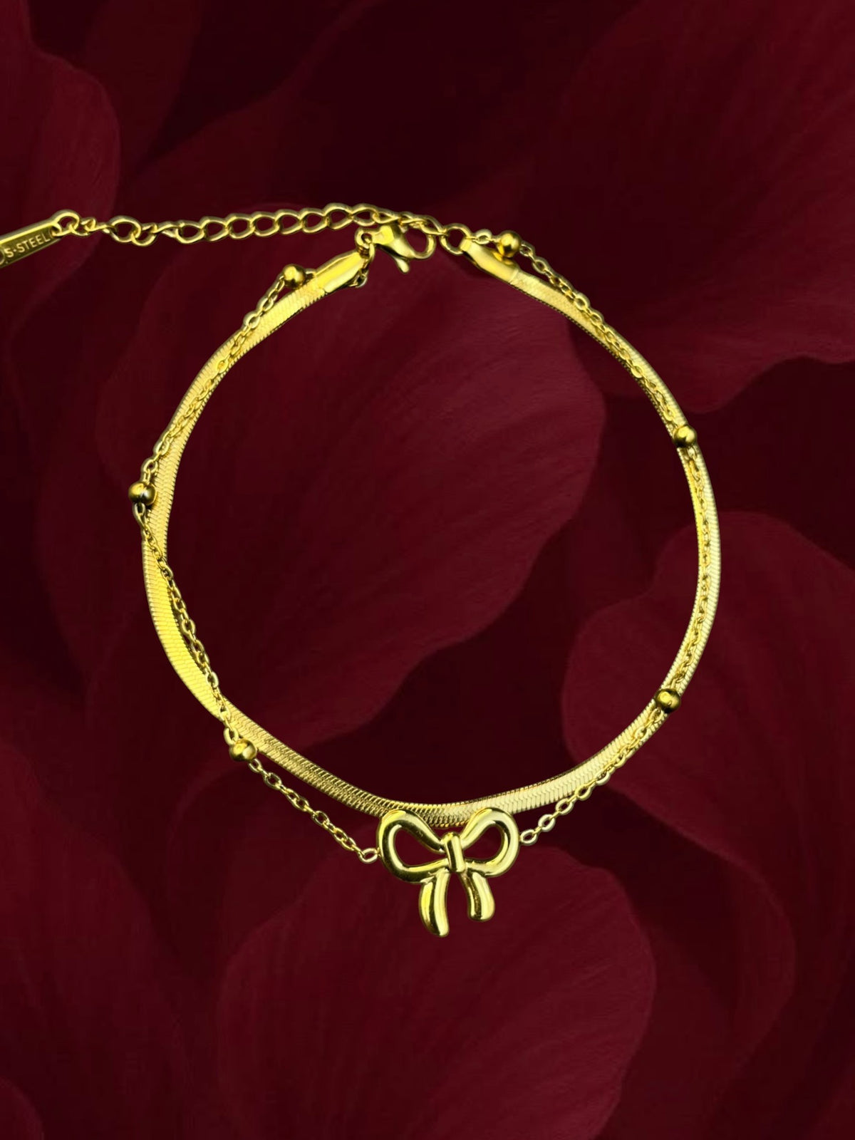 SHE BEAUTY KIYU ZIYU gold-toned double-layer anklet featuring a delicate bow charm and a sleek herringbone chain.