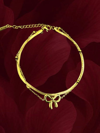 SHE BEAUTY KIYU ZIYU gold-toned double-layer anklet featuring a delicate bow charm and a sleek herringbone chain.