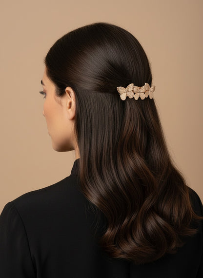 SHE BEAUTY metallic butterfly barrette worn in dark hair, featuring a gold-toned finish for festive party styling.