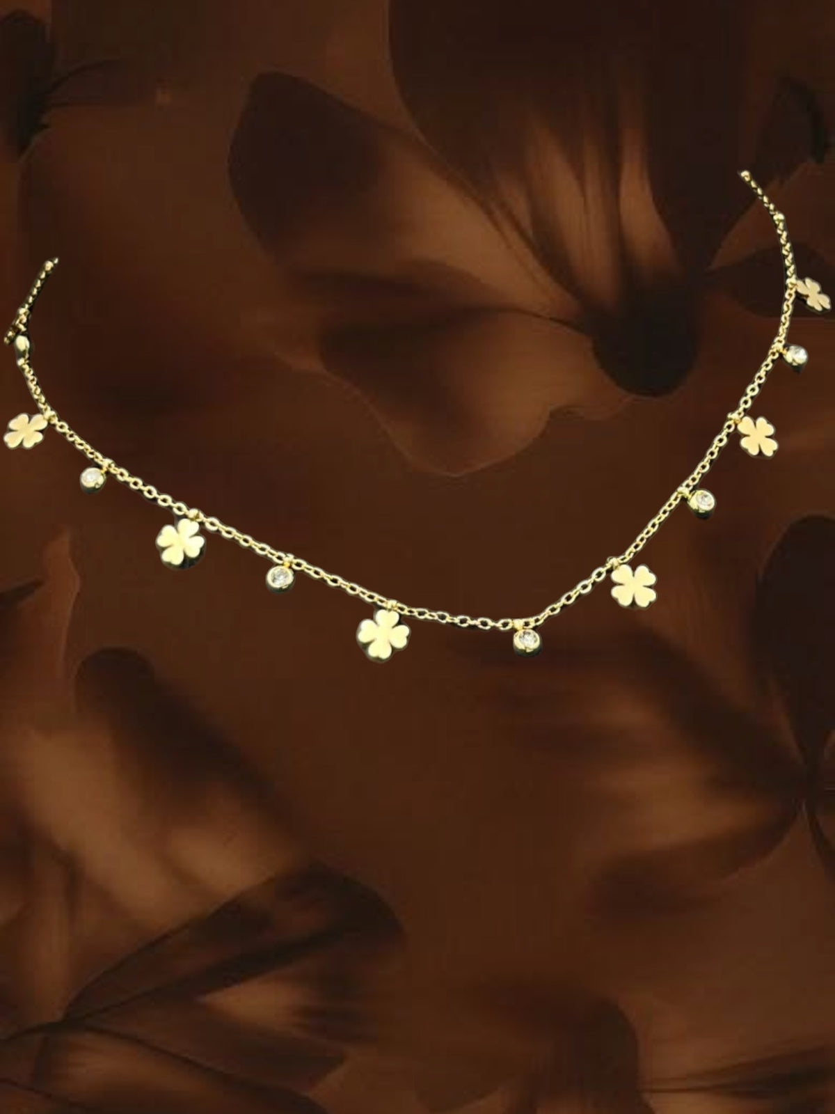 SHE BEAUTY gold-tone chain necklace featuring alternating clover charms and small clear crystals for festive wear.