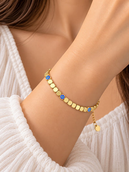 SHE BEAUTY gold-toned chain bracelet featuring small blue evil eye charms worn on a woman's wrist