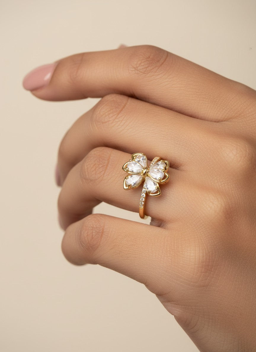 SHE BEAUTY gold-toned anti-tarnish ring featuring a sparkling floral design with clear AD stones on a woman's finger.
