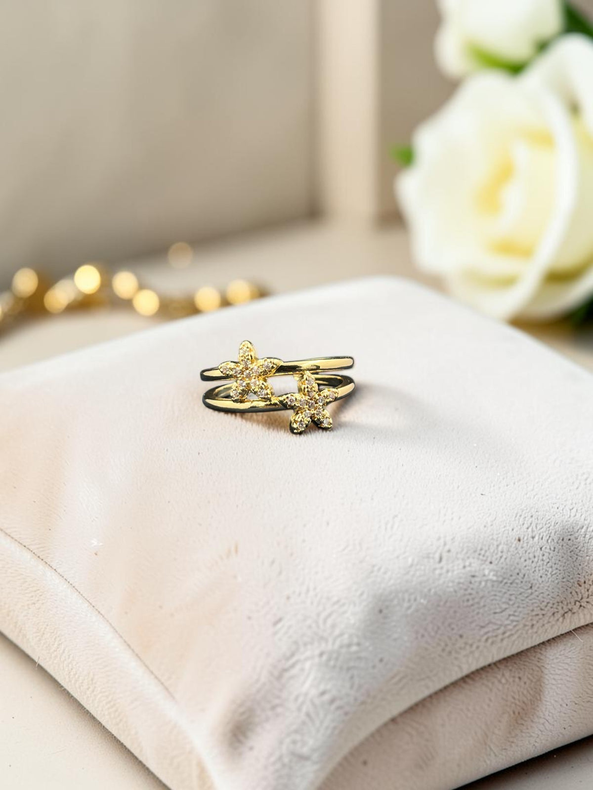 SHE BEAUTY anti-tarnish gold-tone ring featuring two delicate flower motifs with sparkling AD stones on a velvet pad.