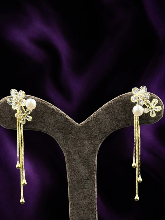 SHE BEAUTY AD Bloom Trail earrings featuring gold-tone flower studs with crystals, pearls, and dangling chain tassels.