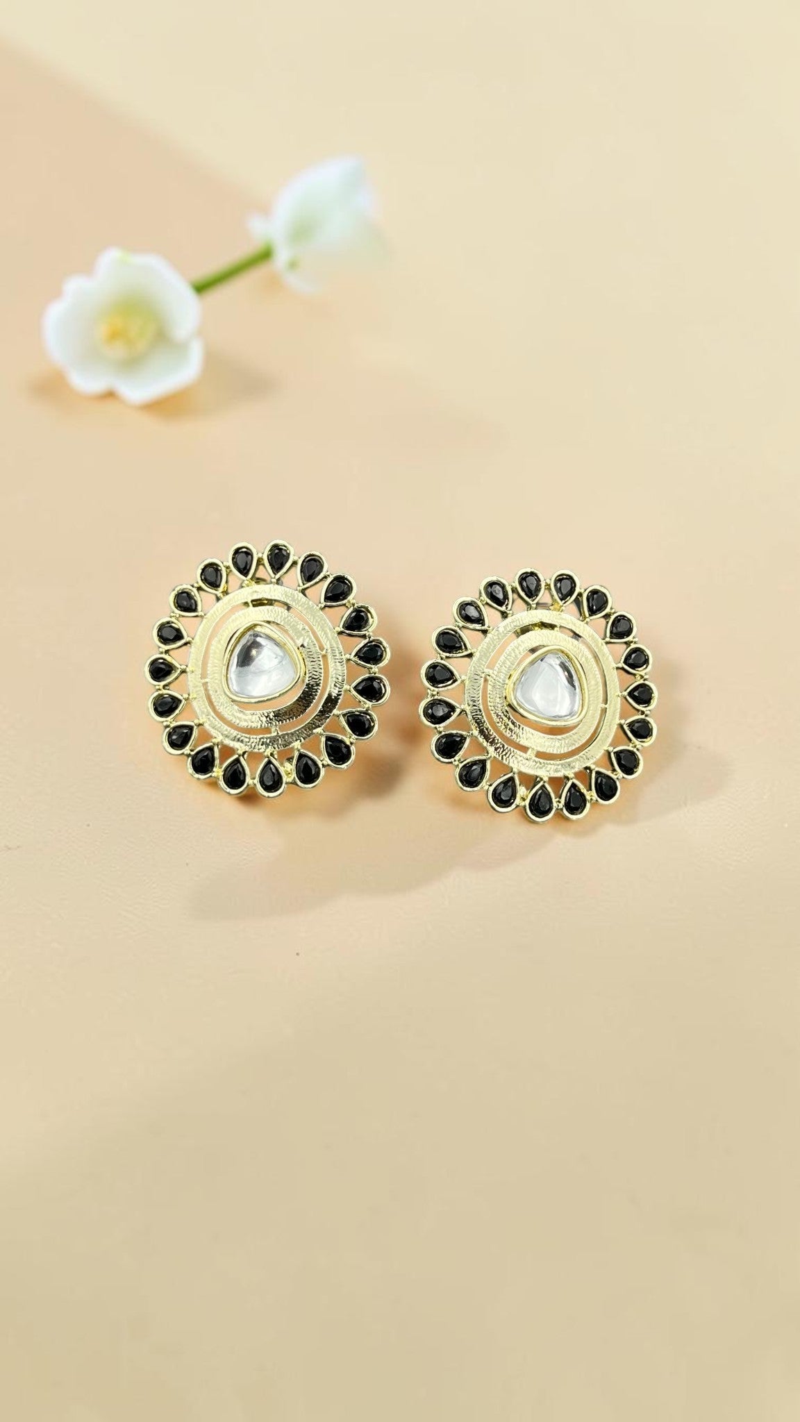SHE BEAUTY gold-toned kundan stud earrings featuring a central teardrop stone surrounded by black teardrop accents.