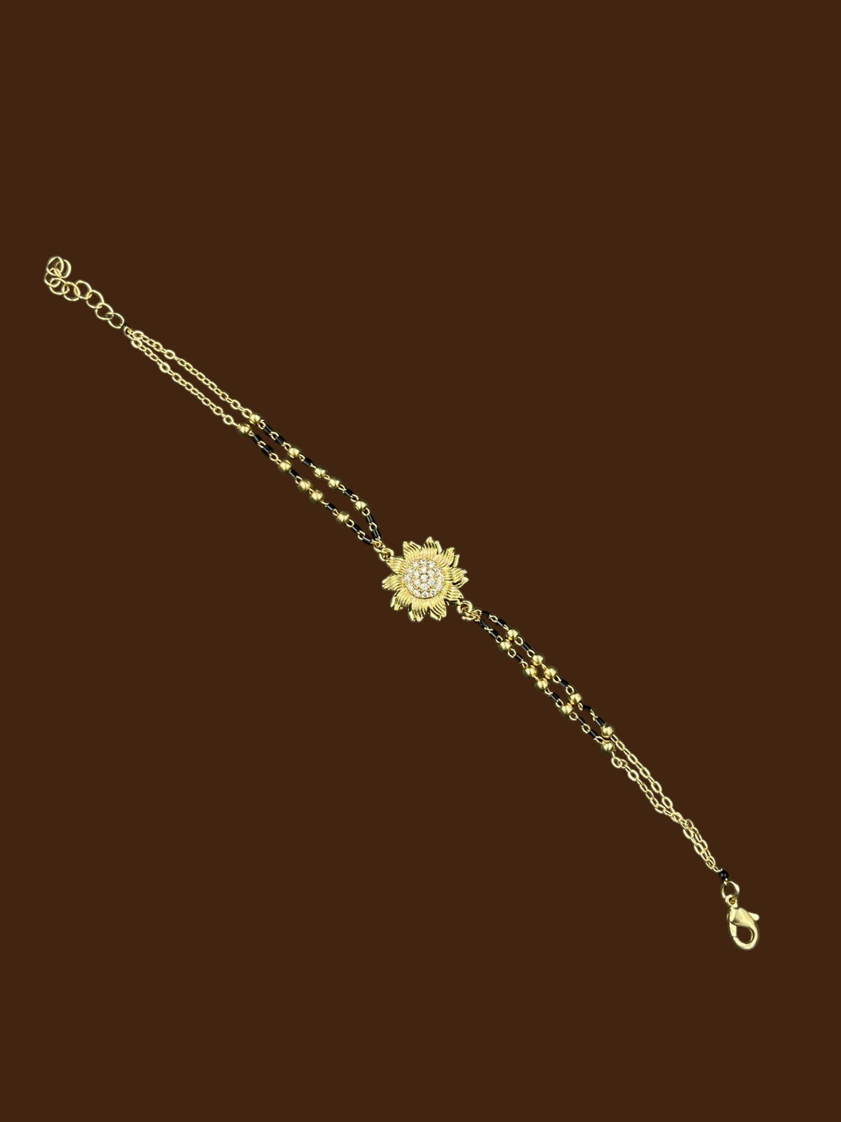 SHE BEAUTY anti-tarnish gold-toned mangalsutra bracelet with a central sunflower-shaped AD stone pendant.