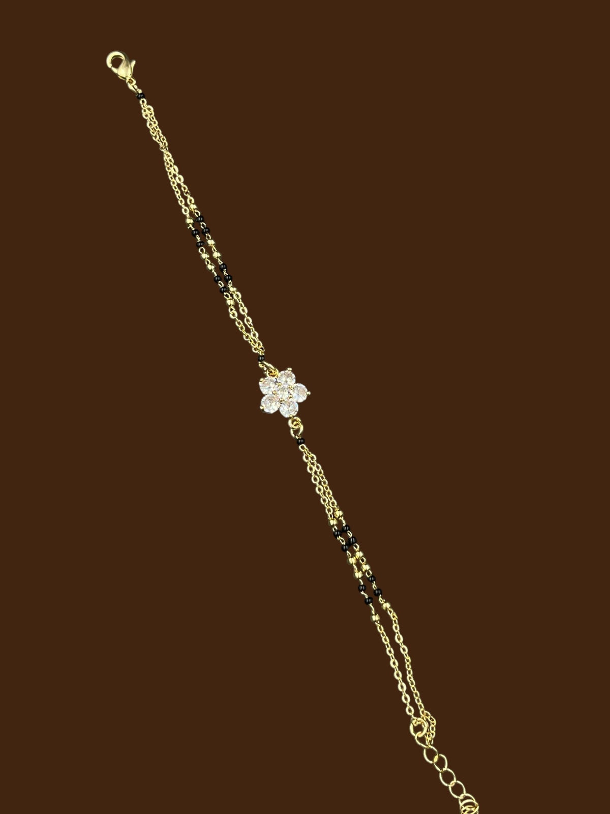 SHE BEAUTY anti-tarnish gold-plated mangalsutra bracelet featuring a delicate flower charm with sparkling AD stones.
