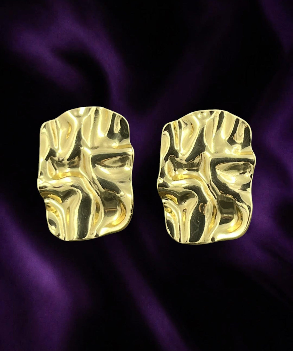 SHE BEAUTY gold-toned anti-tarnish earrings with a unique abstract molten metal texture on a purple satin background