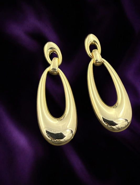 SHE BEAUTY Korean Muse gold-toned drop earrings with a polished oval design on a deep purple satin background