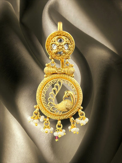 SHE BEAUTY gold-toned peacock Juda hair brooch with ruby stones and pearl accents on a dark satin background.