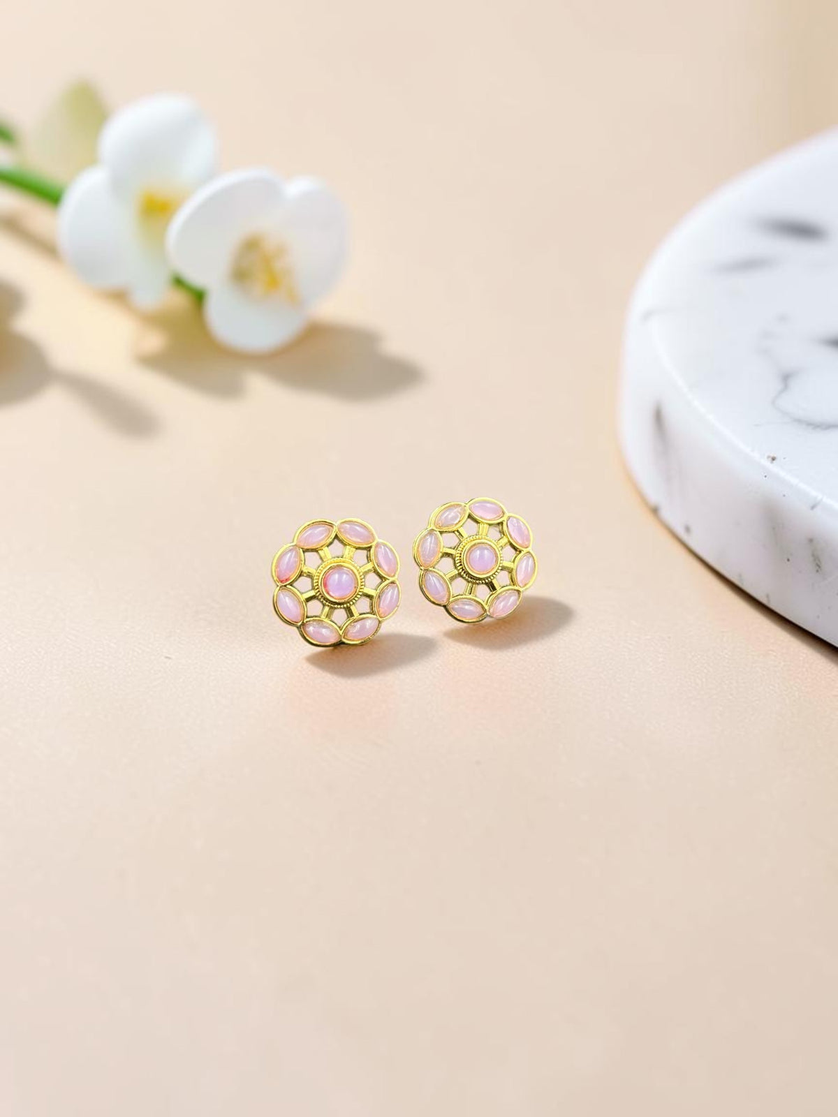 SHE BEAUTY gold-toned stud earrings featuring a floral-inspired design with soft pink cabochon stones