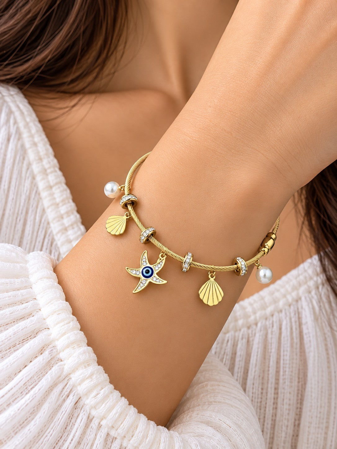 SHE BEAUTY gold-tone cable bracelet featuring a starfish charm with an evil eye, seashell charms, and white pearls.