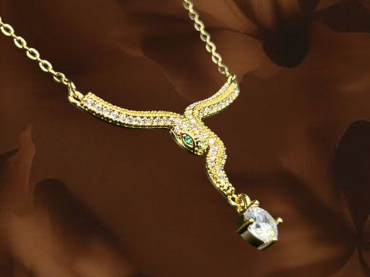 SHE BEAUTY gold serpent pendant necklace featuring sparkling cubic zirconia stones and a green eye detail