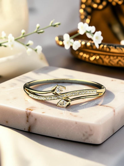 SHE BEAUTY gold anti-tarnish bracelet featuring a bypass design with sparkling zirconia stones on a marble display