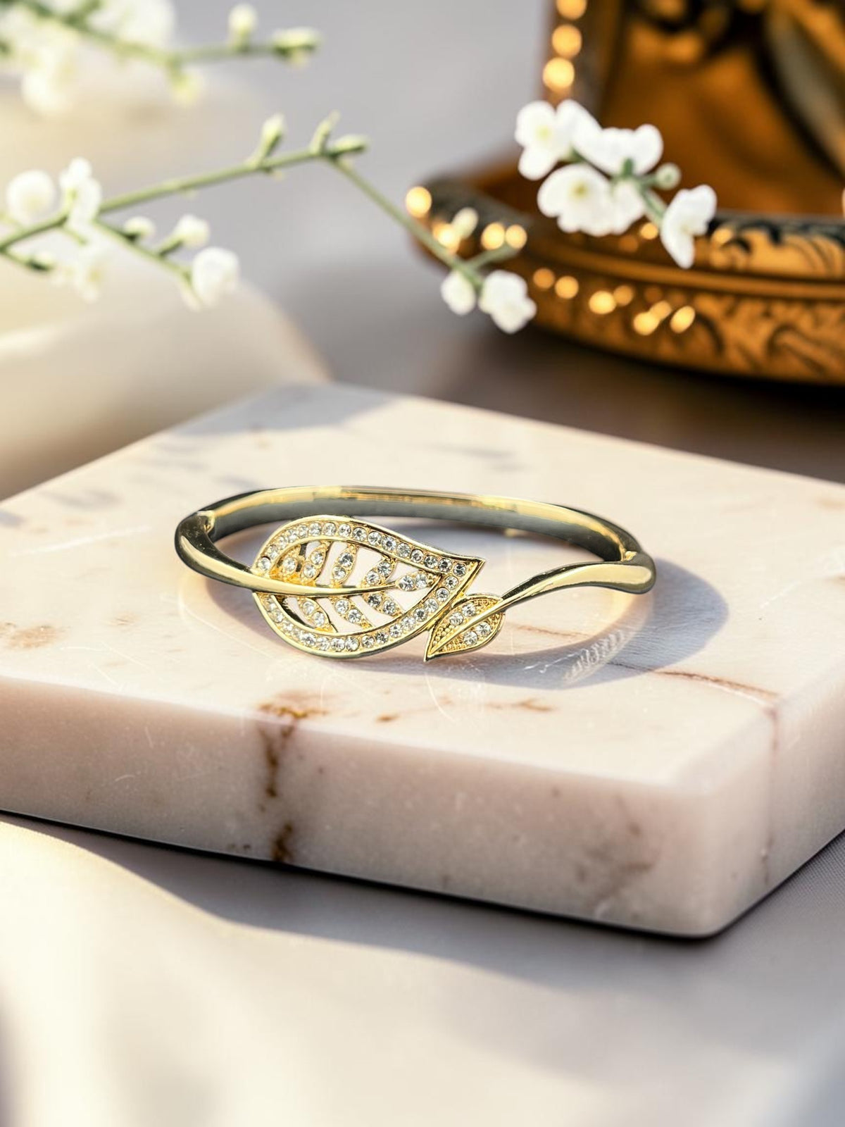 SHE BEAUTY gold-tone anti-tarnish bracelet featuring a delicate leaf motif encrusted with sparkling zirconia stones.