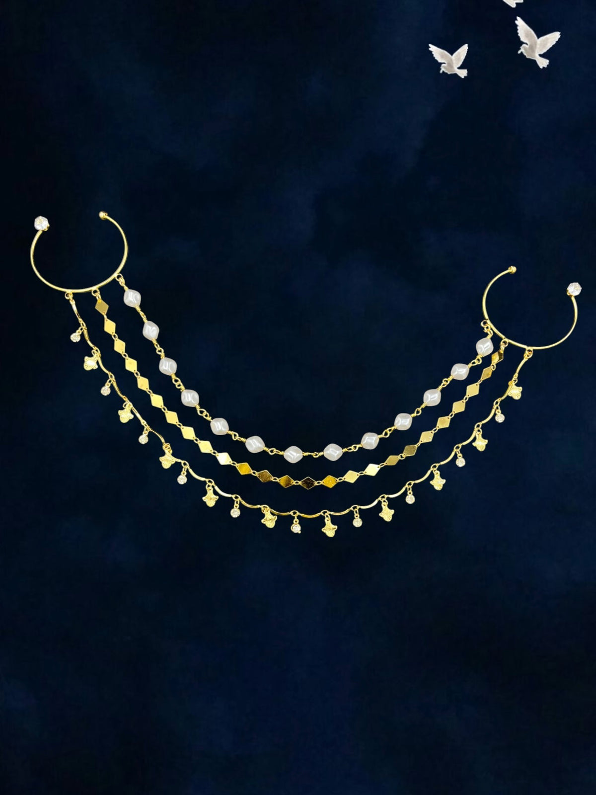 SHE BEAUTY golden braid pearl loop hair accessory with multi-layered chains, beads, and charms on a dark background.