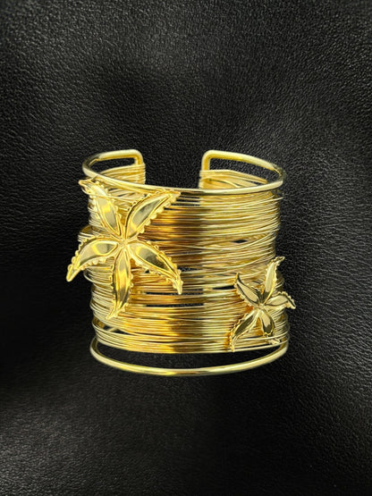 SHE BEAUTY golden multilayer cuff bracelet featuring delicate starflower accents on a black leather background