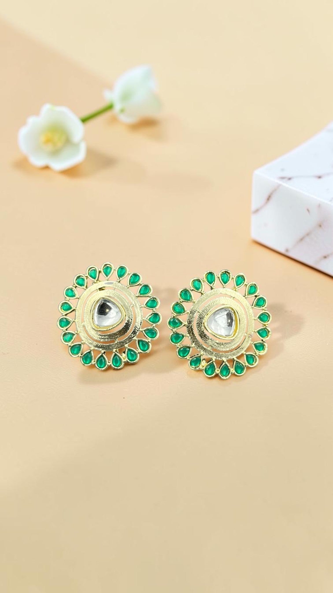 SHE BEAUTY round kundan tops with a central stone surrounded by green teardrop accents in a gold-tone finish.