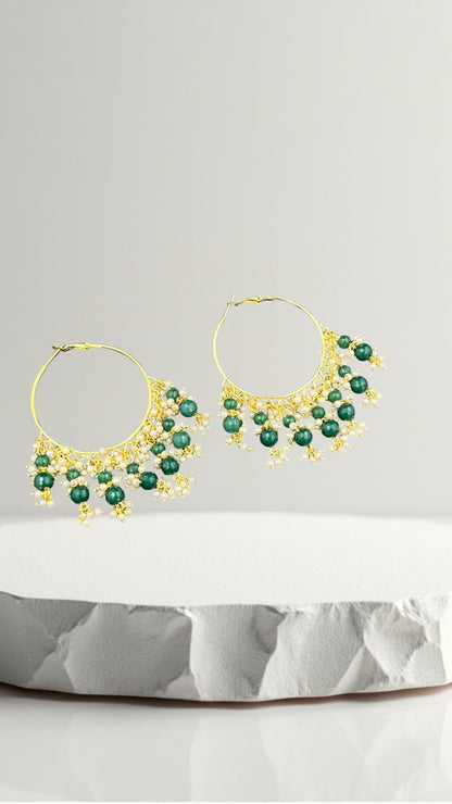 SHE BEAUTY Kashmiri Bali gold hoop earrings featuring green beads and small white pearls on a white stone display
