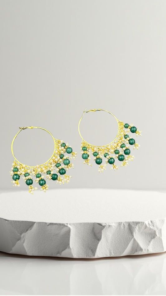 SHE BEAUTY Kashmiri Bali gold hoop earrings featuring green beads and small white pearls on a white stone display