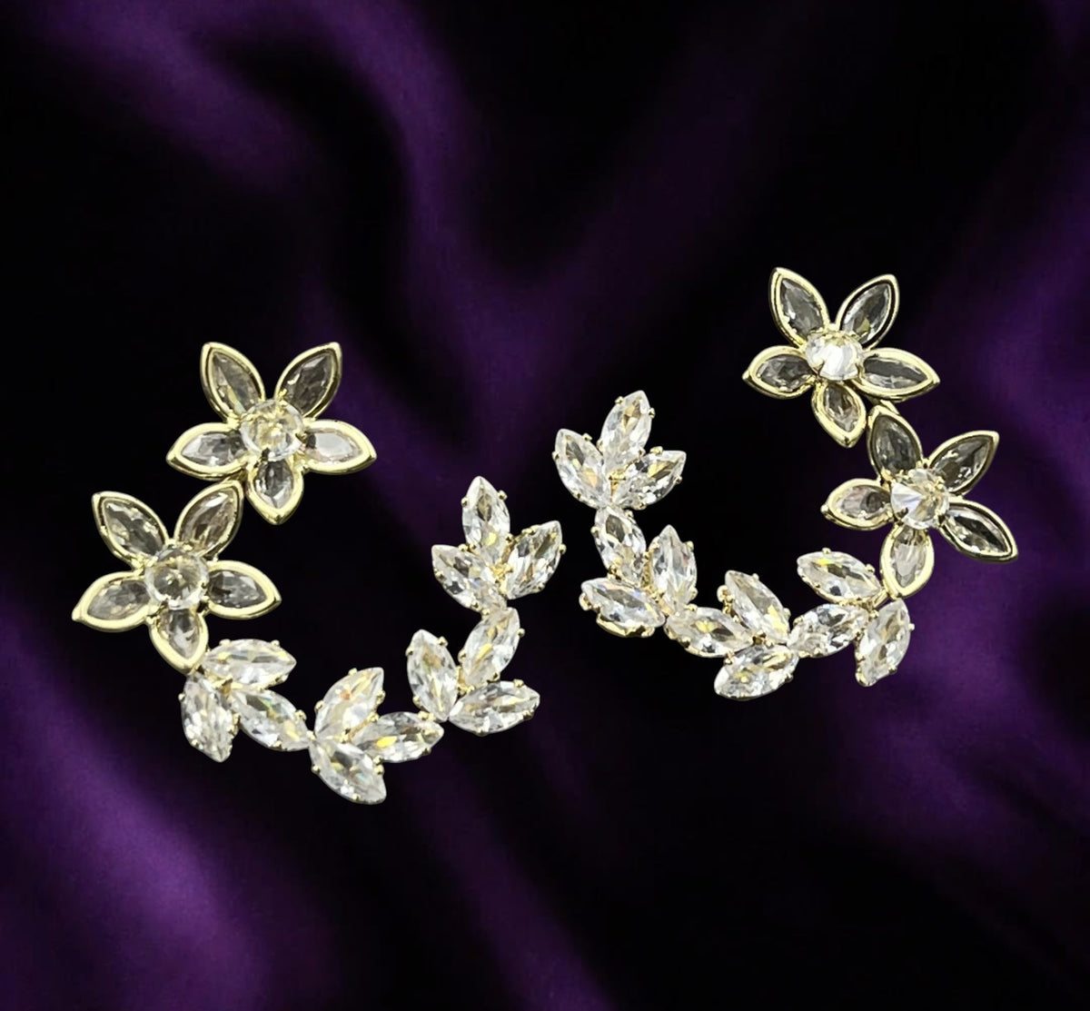 SHE BEAUTY KOREAN AD BLOOM floral earrings with clear crystal stones and gold-tone finish on a purple satin background