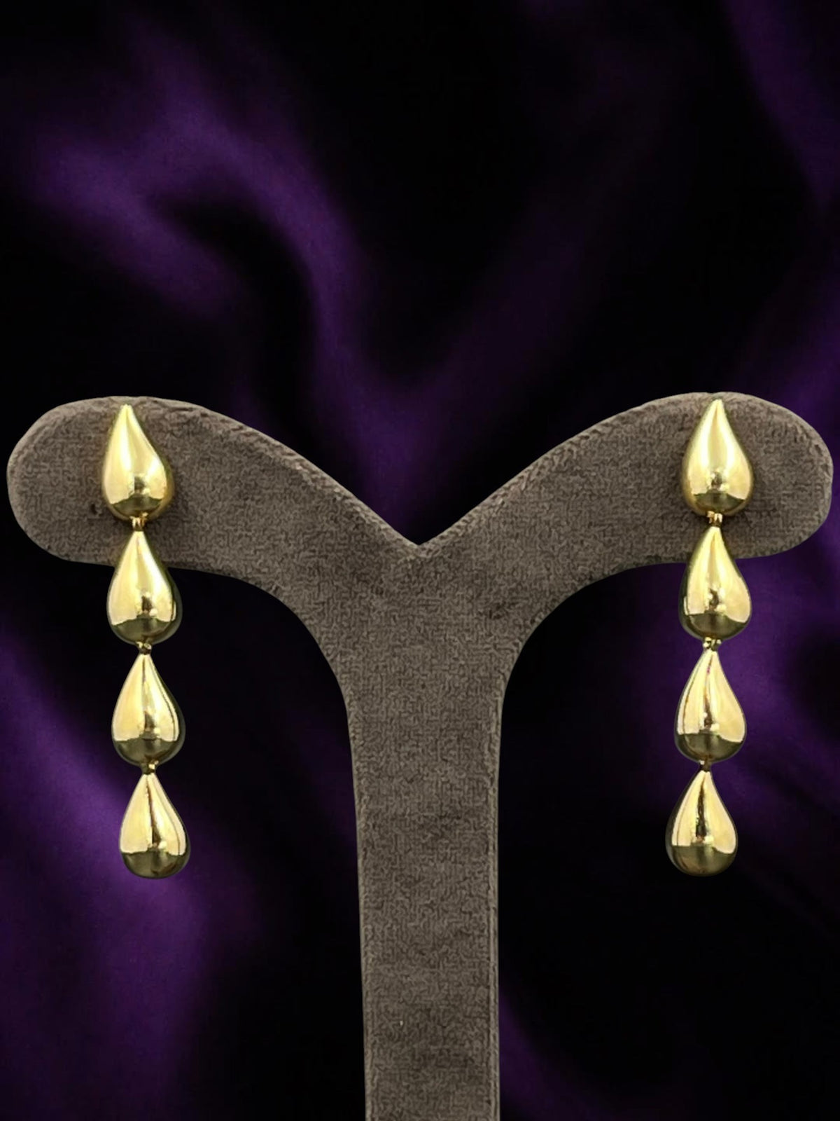SHE BEAUTY KOREAN DROPS gold-toned tiered teardrop earrings for festive and party wear on a display stand